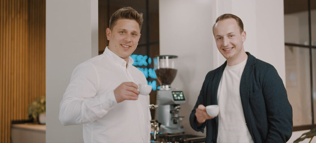 Zwei junge Männer trinken gemeinsam Kaffee und wirken motiviert
