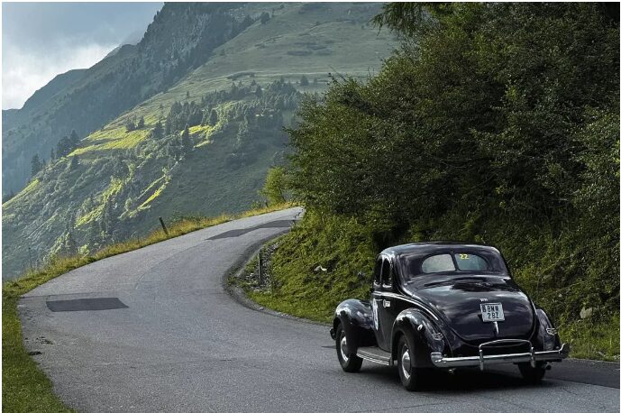 Schwarzer Oldtimer fährt auf einer Straße im Gebirge